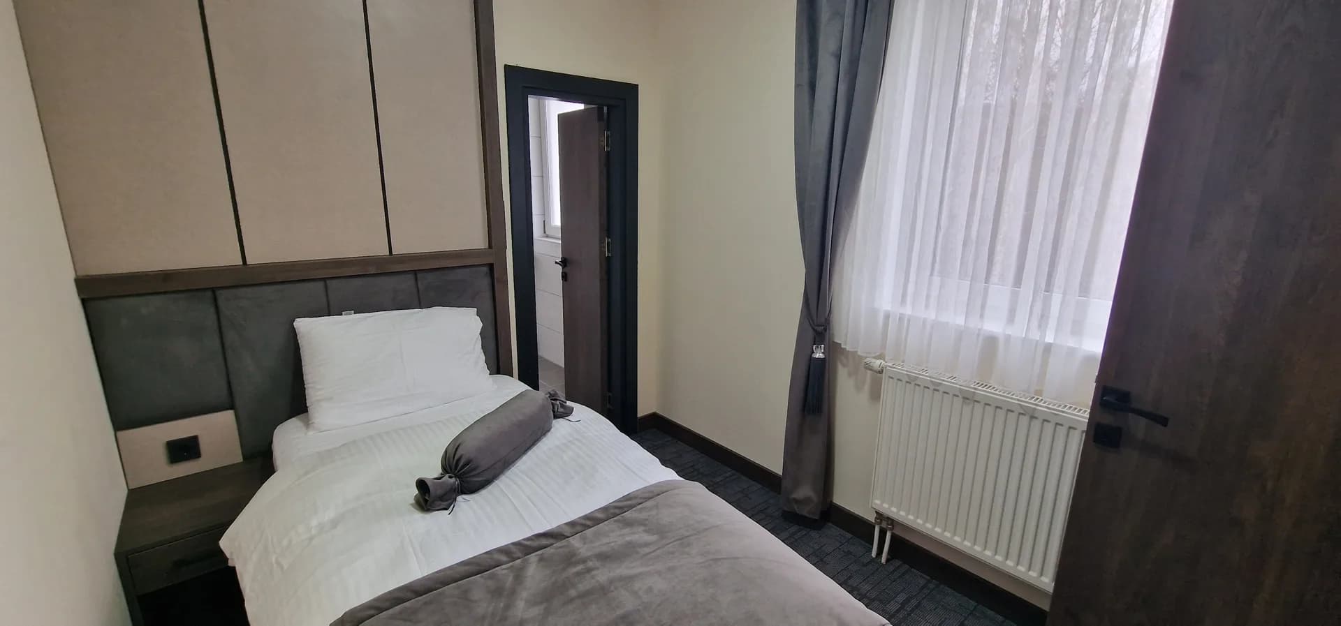 Einzelzimmer mit gepolstertem Kopfteil.