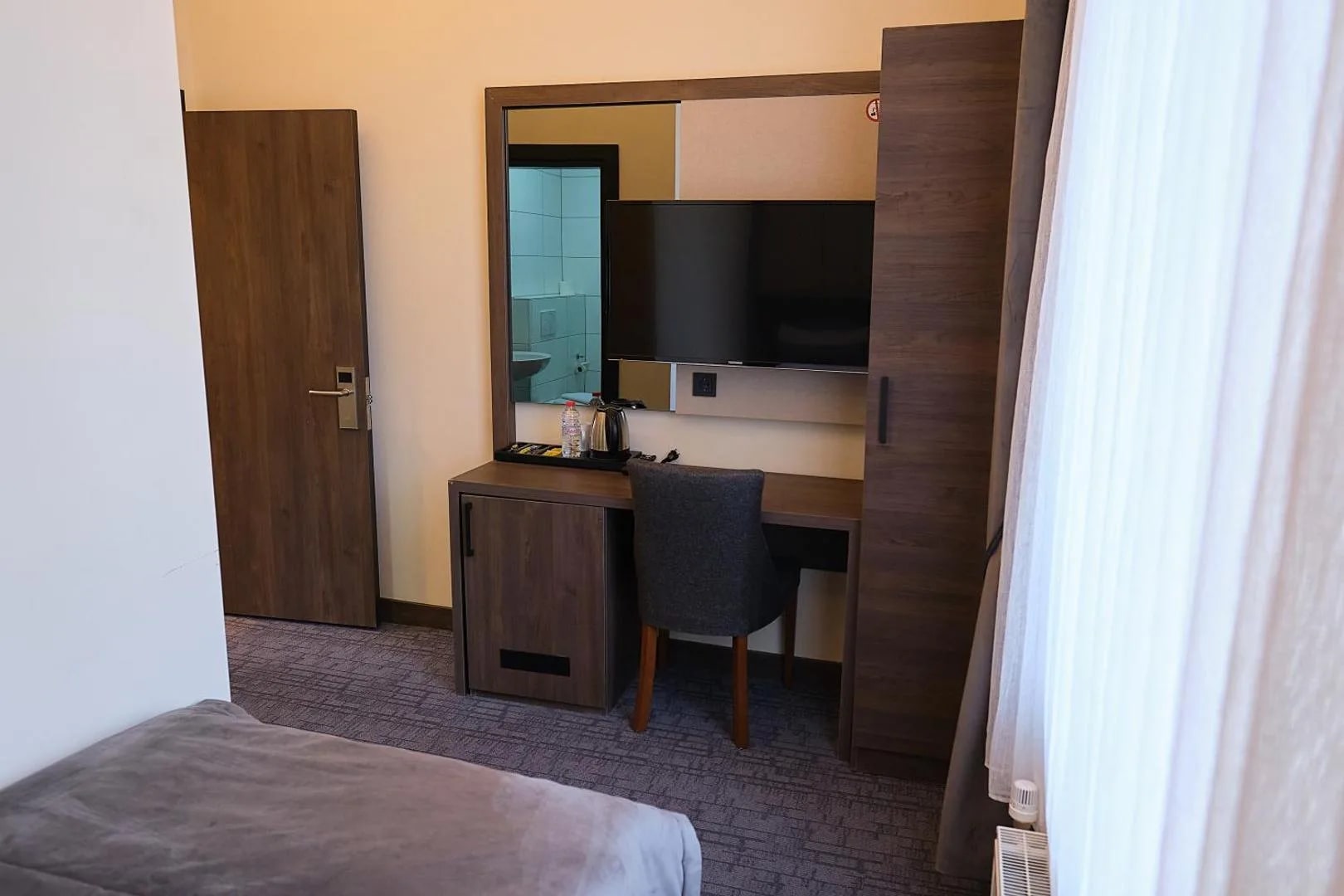 Einzelzimmer mit Schreibtisch, Spiegel und Flat-TV