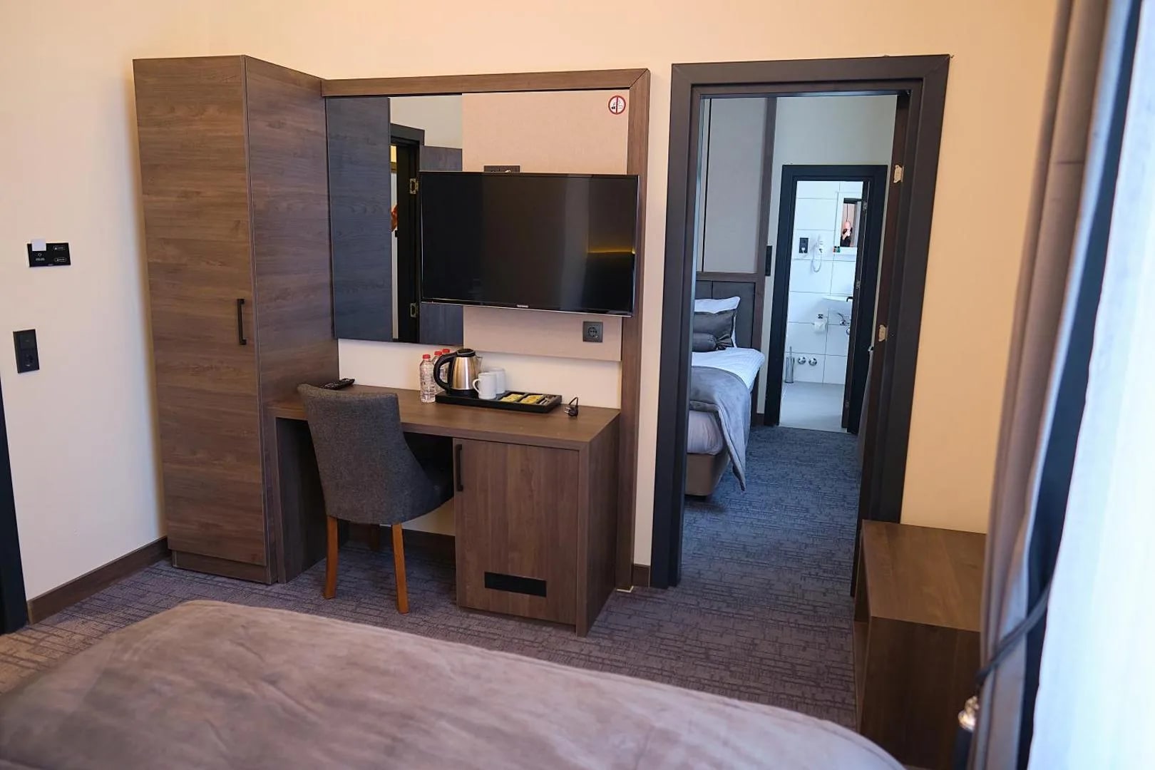 Dreibettzimmer mit Schrank, Schreibtisch und Flat-TV